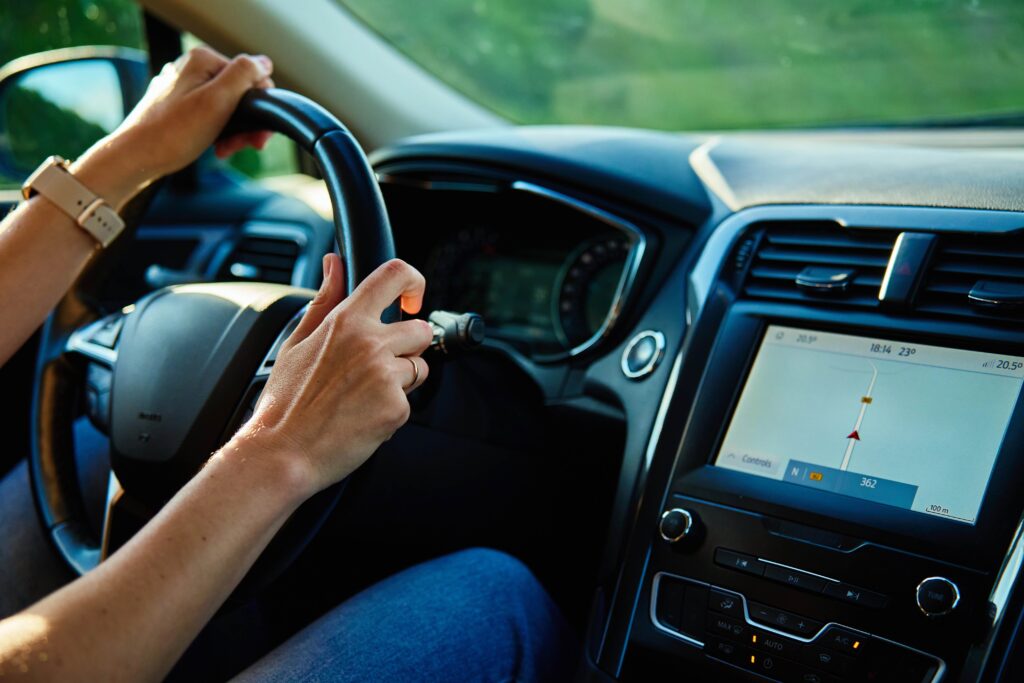 Hombre maneja su auto por la carretera mientras su gps le indica el camino